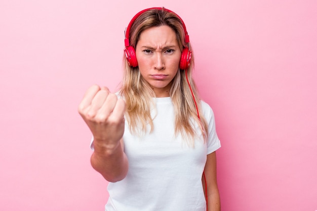 Música jovem australiana isolada no fundo rosa, mostrando o punho para a câmera, expressão facial agressiva.