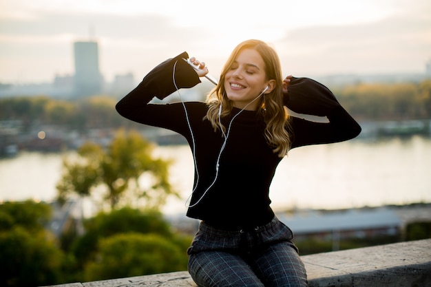 Foto música jovem na moda do smartphone ao ar livre ao pôr do sol