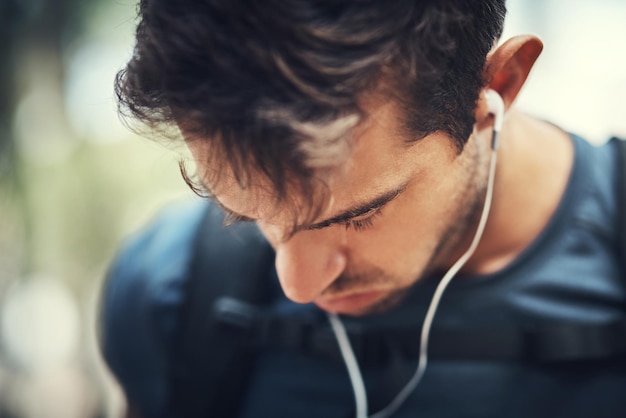 La música lo mantendrá motivado Captura de pantalla de un apuesto joven escuchando música mientras camina por las montañas