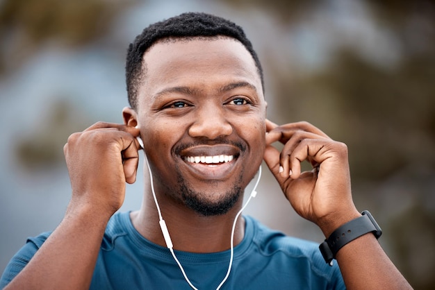La música me mantiene sincronizado con mis movimientos. Foto de un joven deportivo escuchando música mientras hace ejercicio al aire libre.