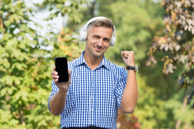 Música móvil Hombre feliz escuchar música en los auriculares Vida moderna Tecnología móvil Estilo de vida móvil Disfrutar de la reproducción de música en el teléfono móvil