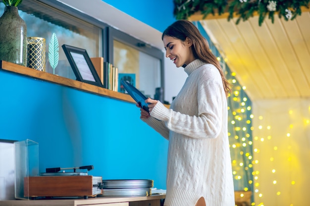 Música. Mujer morena vestida de blanco con un disco en sus manos