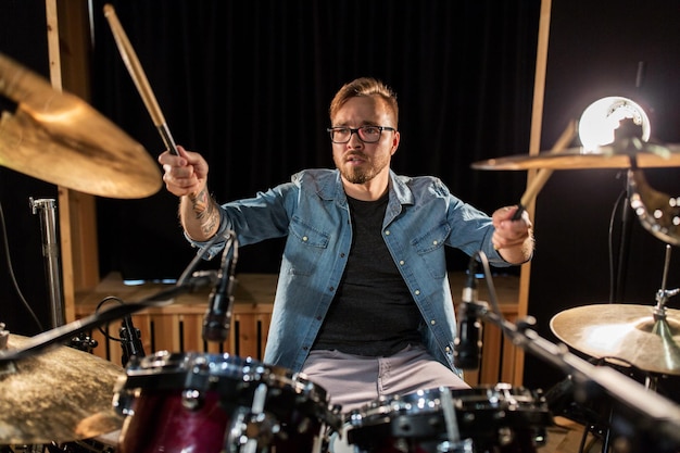 música, pessoas, instrumentos musicais e conceito de entretenimento - músico masculino com pauzinhos tocando bateria e címbalos em concerto ou estúdio