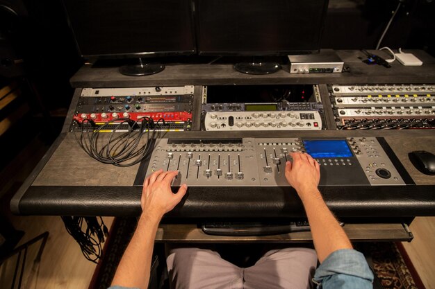 música, tecnologia, pessoas e equipamento conceito - homem usando console de mistura em estúdio de gravação de som