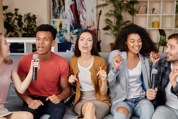 La música trae alegría a los entusiastas amigos multiculturales que cantan con el micrófono mientras juegan al karaoke