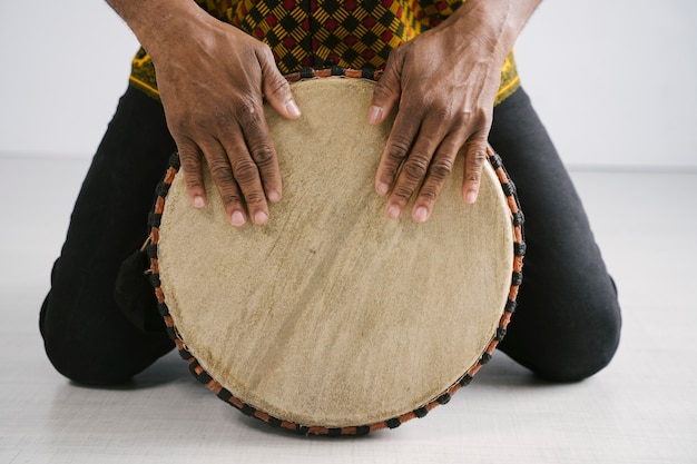 Músico afroamericano masculino tocando la batería tradicional en casa. Concepto de clase de música en línea. Ocio y aprendizaje de instrumentos musicales. Ritmo en tradiciones étnicas multiculturales.