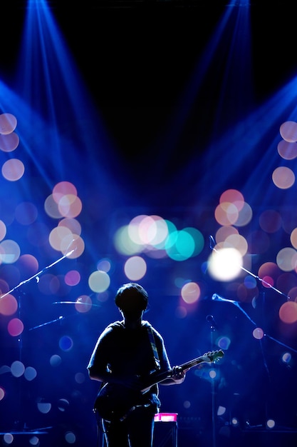 Foto músico asiático tocando la guitarra sobre fondo negro con foco y destello de lente concepto musical