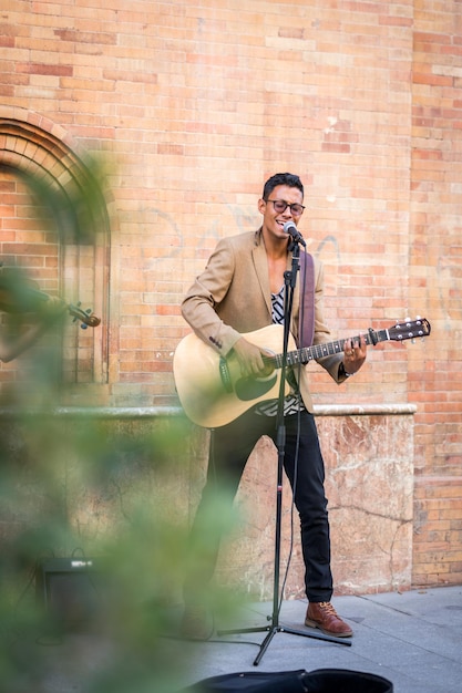 Foto músico callejero cantando y tocando la guitarra en la calle