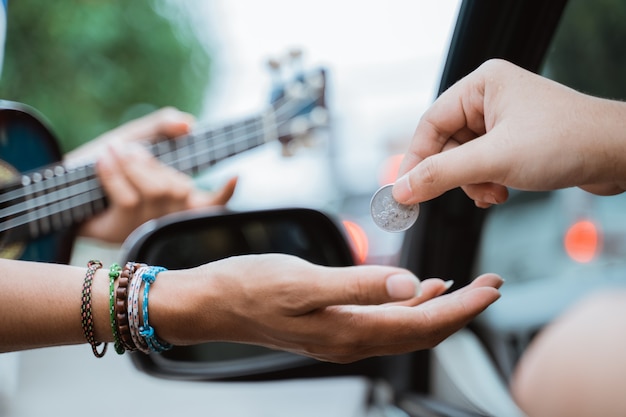 Músico callejero masculino pidiendo dinero en el semáforo