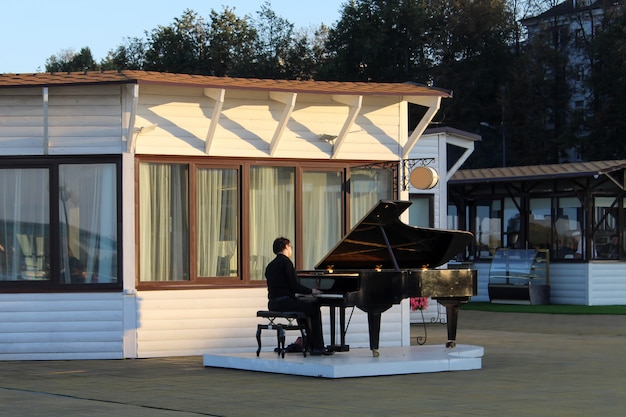 Músico callejero tocando el piano junto al mar en Europa