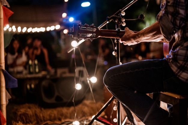 Un músico con una camisa a cuadros está tocando la guitarra en el escenarioConcertmini concierto y festival de música