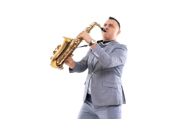 Foto músico emocional masculino en un traje toca el saxofón aislado sobre fondo blanco.