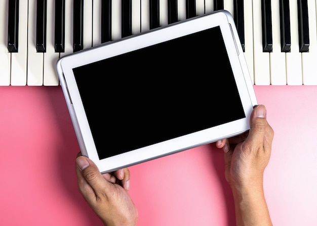 Músico está sosteniendo la pantalla de la tableta en blanco para simulacro de aplicación de música