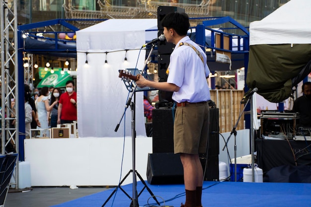 Músico estudiante tailandés tocando música clásica instrumento de guitarra en el escenario en el evento del festival para mostrar a los viajeros en el patio al aire libre en el centro comercial del departamento de Iconsiam el 25 de febrero de 2023 en Bangkok Tailandia