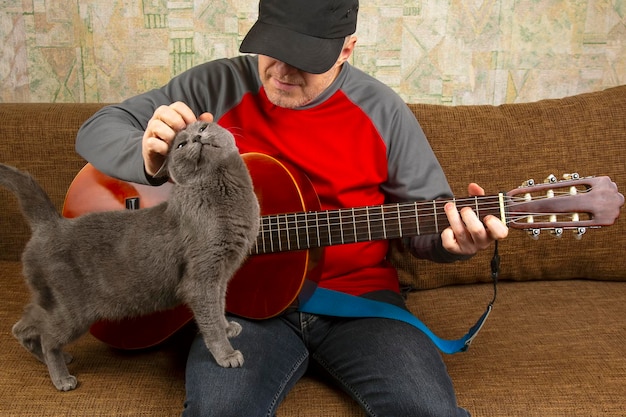 Músico con una guitarra clásica sentado en el sofá con un gato