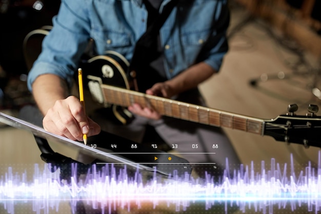 Foto músico con guitarra y libro de música en el estudio