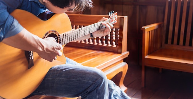 músico hipster tocando guitarra acústica o practicando guitarra para unas vacaciones relajantes en casa