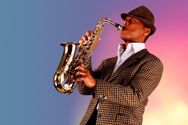 Foto músico de jazz guapo afroamericano tocando el saxofón en el estudio sobre un fondo de neón.