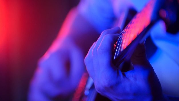 Músico jovem tocando guitarra em iluminação neon