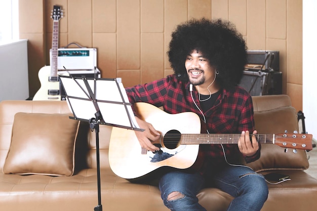 Músico con las manos en la guitarra dentro del estudio de grabación