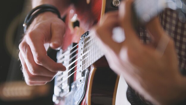 Músico masculino toca guitarra, mãos fechadas, foco no braço da guitarra, conceito de arte