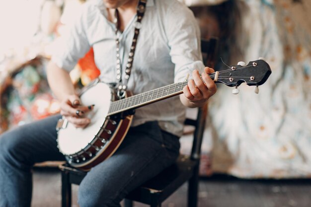 Músico masculino tocando banjo sentado na cadeira interior