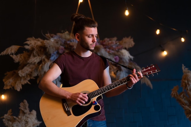 Músico masculino tocando guitarra acústica guitarrista toca guitarra clásica en el escenario en concierto