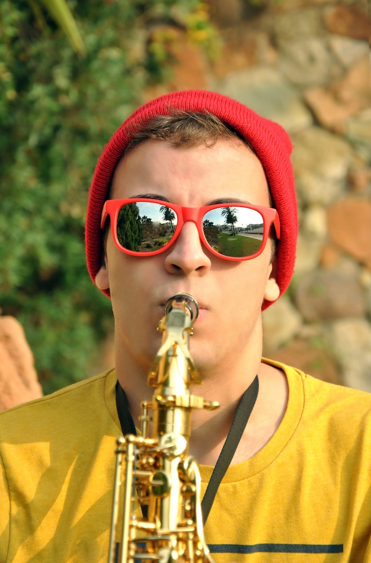Foto músico moderno posando con su saxofón en el jardín