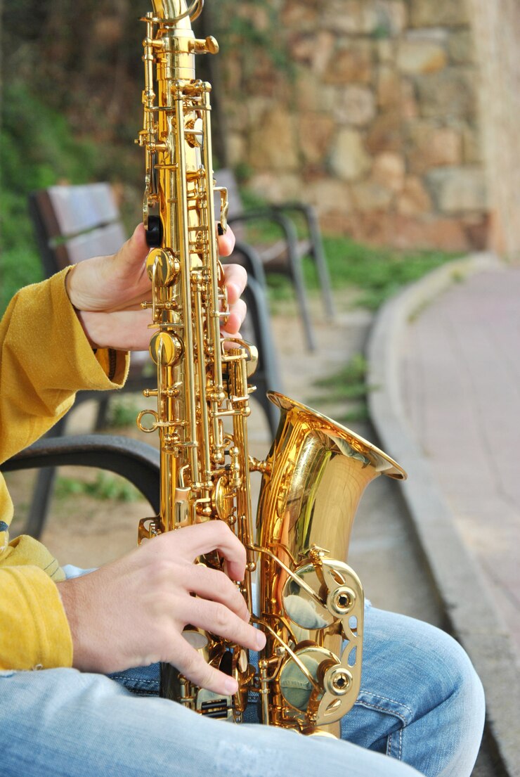 Foto músico moderno posando con su saxofón en la playa