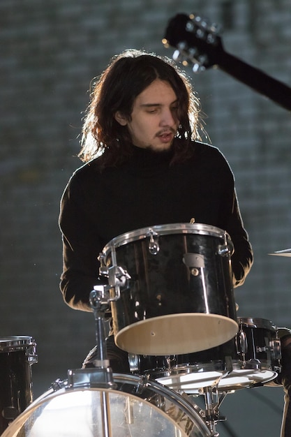 Un músico con el pelo largo sentado junto a la batería.