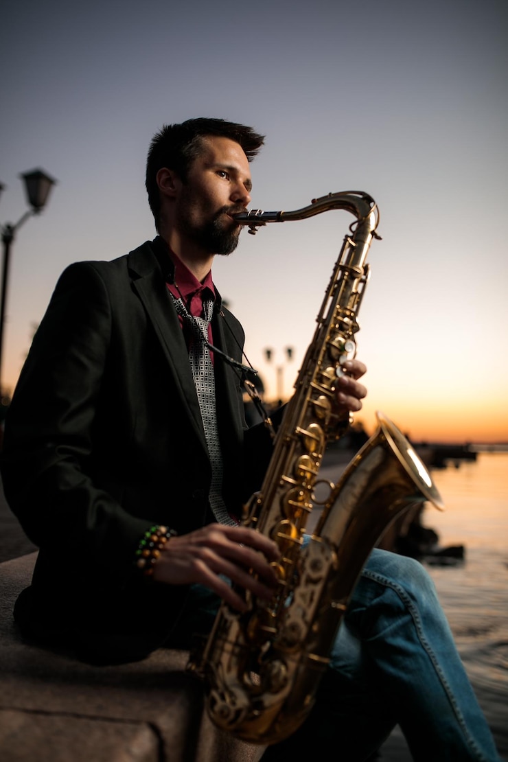 Foto un músico con una percha se sienta en el paseo marítimo por la noche al atardecer