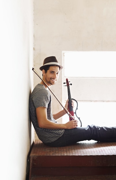 Músico de retrato y hombre con una sonrisa de violín y entrenamiento para un sonido de interpretación o felicidad en casa Cara de violinista feliz con alegría, creatividad e instrumento con entretenimiento