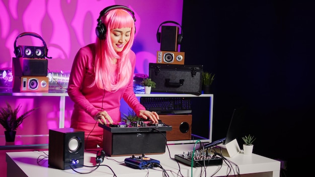 Músico sorridente trabalhando como dj tocando música no console do mixer, misturando música techno com eletrônica usando equipamento de áudio. Artista com cabelo rosa se divertindo em se apresentar no clube durante a noite