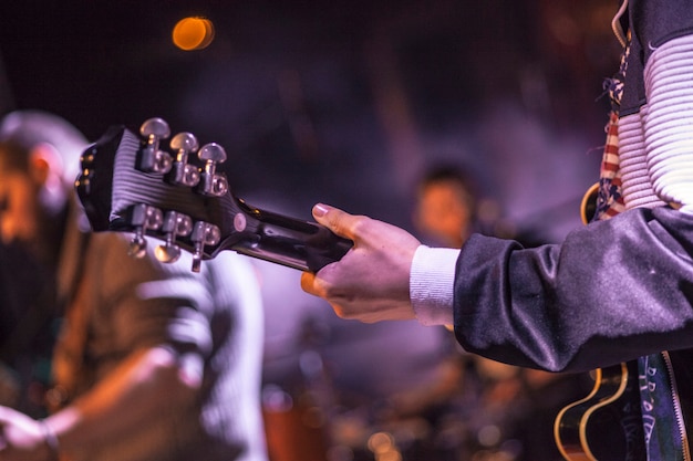 Músico sosteniendo la guitarra durante el concierto en los focos de colores