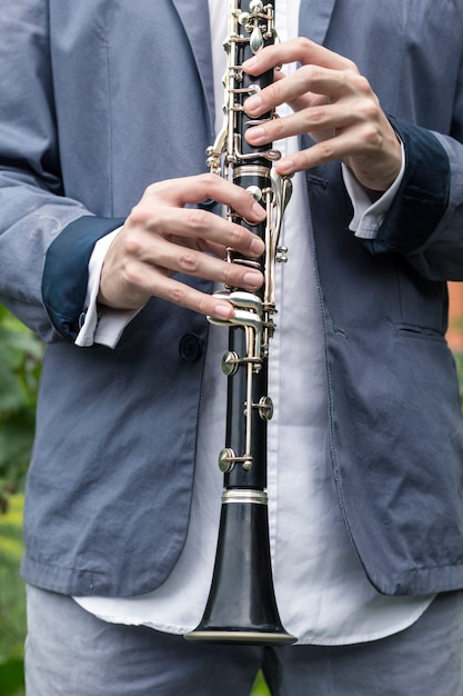 El músico tiene un clarinete en sus manos.