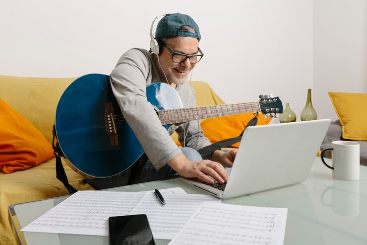 Foto músico tocando la guitarra y componiendo música con sus colegas por videoconferencia a través de su computadora portátil