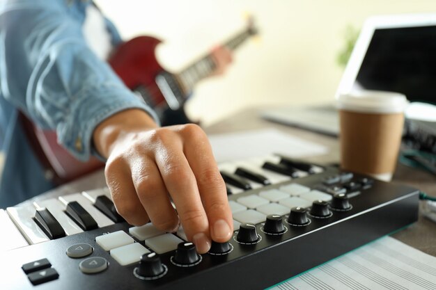 Músico tocando guitarra elétrica e teclado midi, close-up