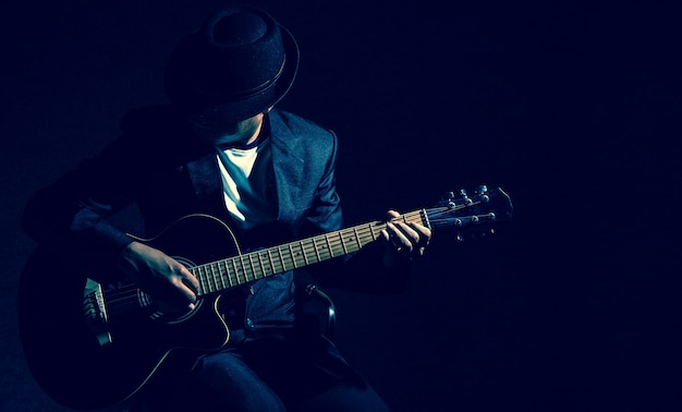 Músico tocando guitarra no fundo preto, conceito de música