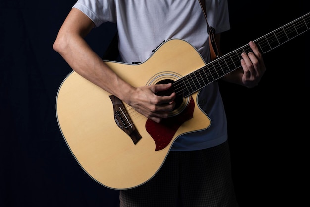 Músico tocando violão no escuro à noite com iluminação lateral