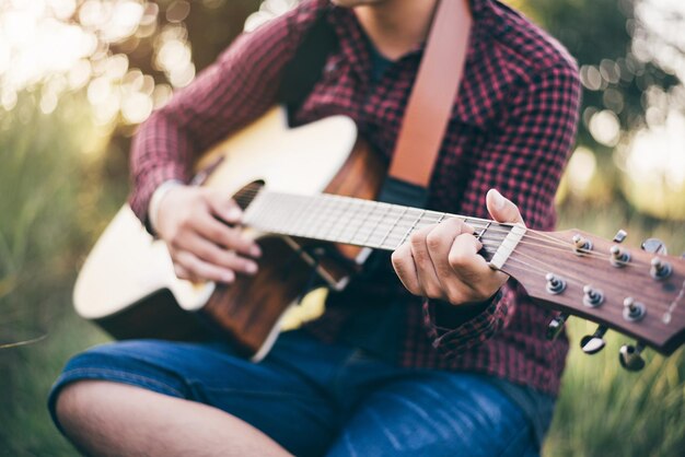 Musik in der Natur Mann mit kariertem Hemd spielt eine akustische Gitarre Nahaufnahme