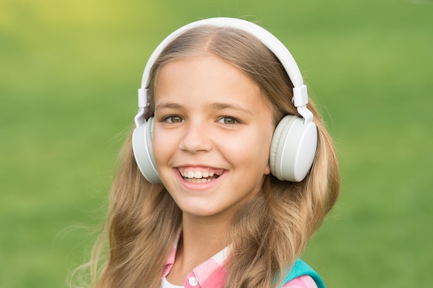 Musik ist Leben. Glückliches Kind hört Musik im Freien. Kleines Mädchen trägt Kopfhörer, die Musik spielen. Musikstunde. Neue Technologie. Modernes Leben. Höre zu und lerne. Spaß und Unterhaltung.
