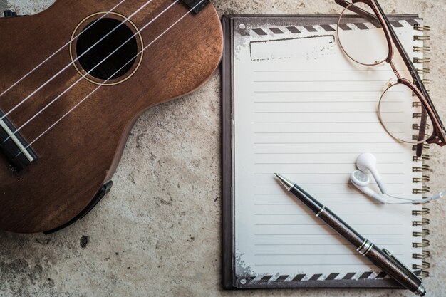 Musik mit Ukulele, Notizblock und Kopfhörer auf Betonboden schreiben. Retro Vintage Filtereffekt.