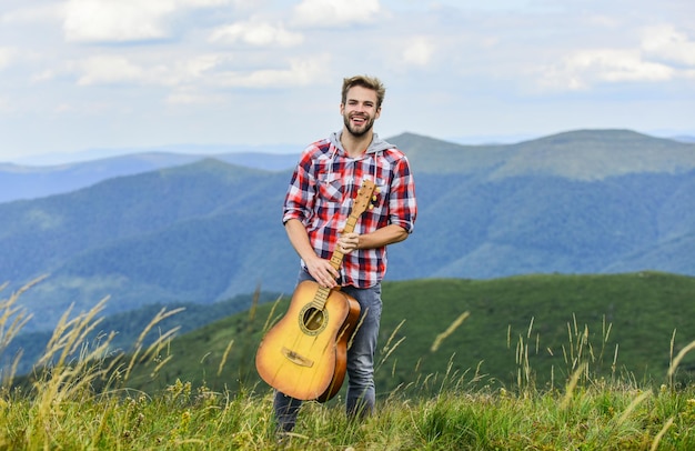 Musik spielen Mann Musiker mit Gitarre auf dem Gipfel Inspirierter Musiker Stille der Berge und Klang der Gitarrensaiten Hipster-Musiker Inspirierende Umgebung Sommermusikfestival im Freien