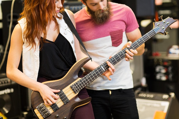 musik, verkauf, menschen, musikinstrumente und unterhaltungskonzept - paar musiker mit gitarre im musikgeschäft