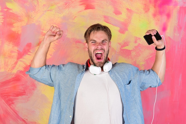 Musikalischer Lebensstil Blauäugiger, stylischer Hipster mit Smartphone