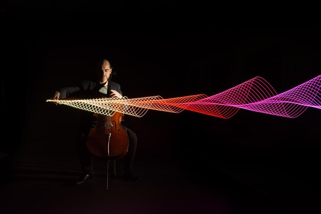 Foto musiker, der cello spielt, in voller länge durch lichtmalerei vor schwarzem hintergrund