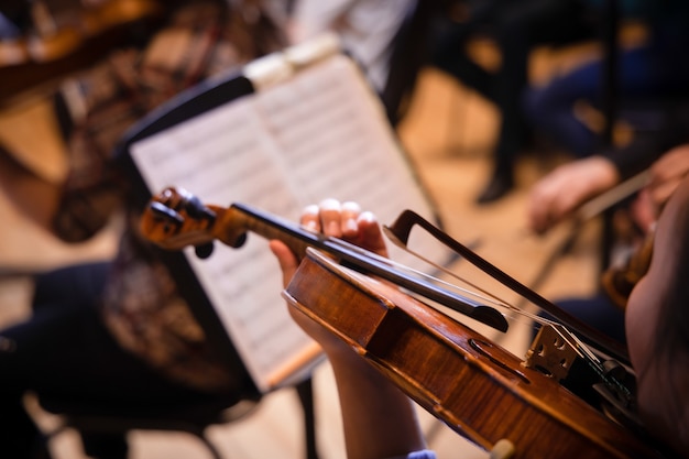 Musiker, der Geige spielt und das Notenblatt während des klassischen Konzerts aus nächster Nähe liest reading