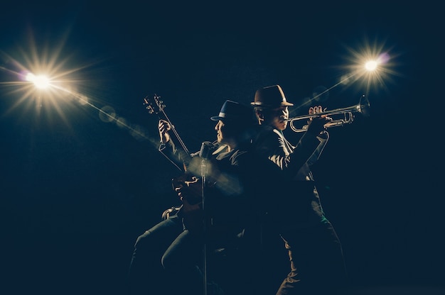 Foto musiker-duo-band, die eine trompete spielt und ein lied singt und die gitarre auf schwarzem hintergrund spielt wi