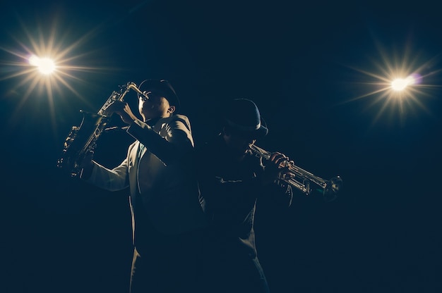 Musiker-Duo-Band, welche die Trompete mit Scheinwerferlicht und Blendenfleck auf der Bühne, musikalisches Konzept spielt