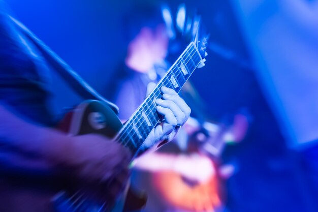 Foto musiker spielt eine elektrische gitarre unter blauer bühnenbeleuchtung